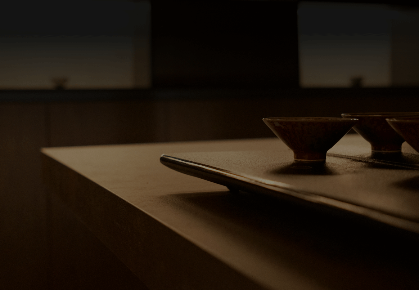 Several handcrafted teacups arranged neatly on a wooden table, creating a calm and refined tea-drinking atmosphere.