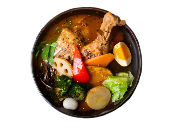 Top-down view of a hearty bowl of Japanese soup curry featuring a roasted chicken leg, soft-boiled egg, lotus root, broccoli, and assorted vegetables.
