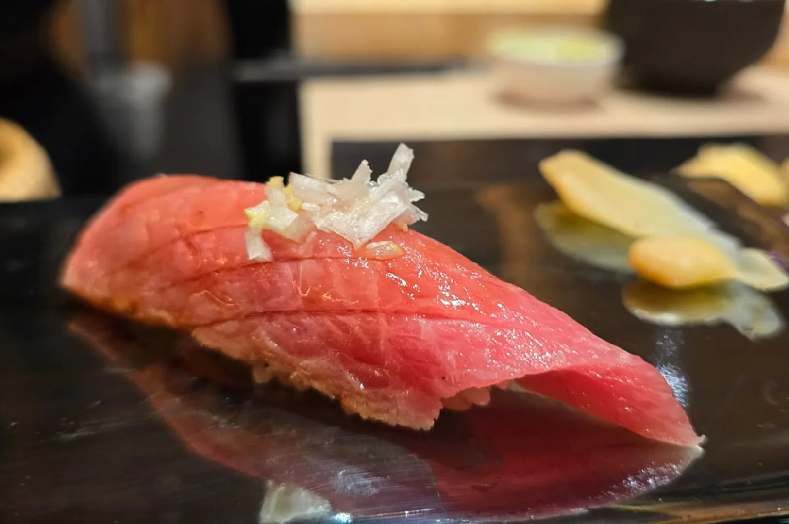 A premium fatty tuna (Otoro) nigiri sushi garnished with finely shredded white leeks (negi) served at an omakase restaurant.