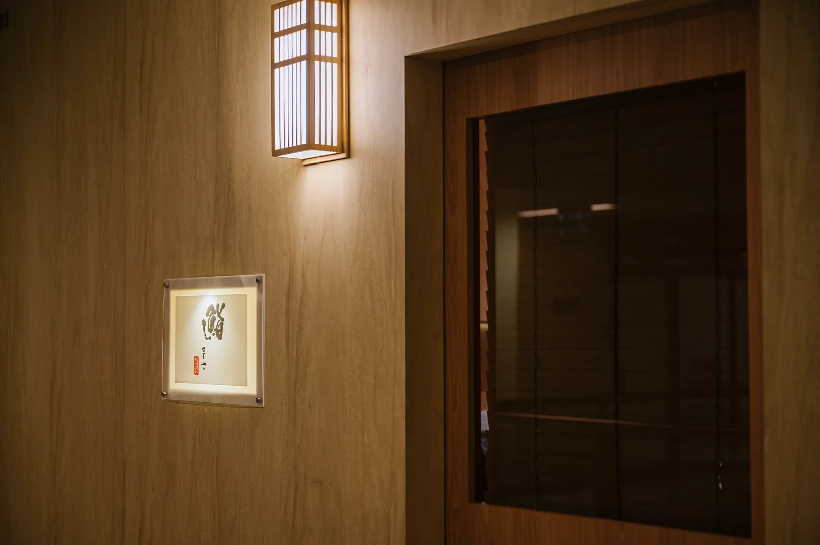 The elegant wooden exterior and glowing signage of a high-end Japanese omakase sushi restaurant.