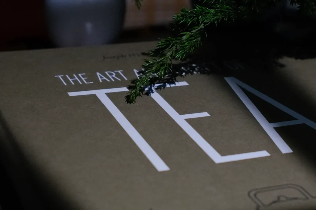 A close-up of a book titled "The Art of Tea" with a branch partially obscuring the title.