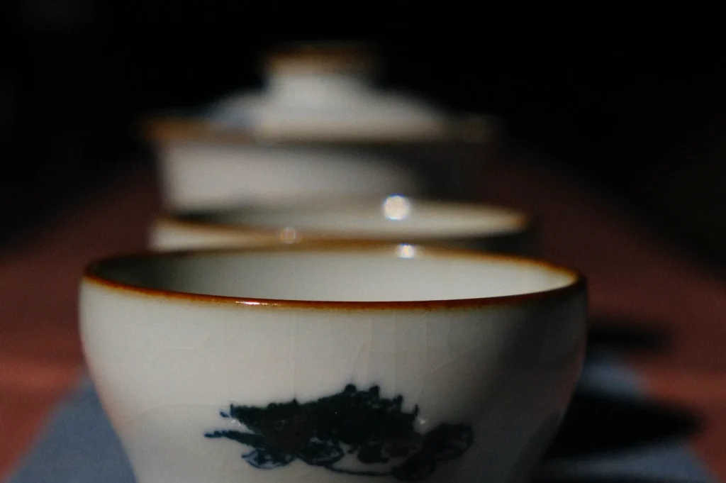 A row of traditional porcelain tea cups with intricate designs and a blurred background.