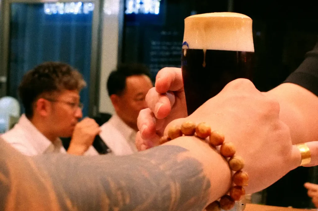 Bartender serving a pint of freshly poured beer with thick creamy foam to a patron at the counter.