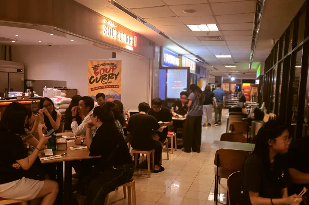 Busy corridor view of diners seated at tables outside Soup Curry and Craft Beer by Ki-setsu in Fortune Centre.